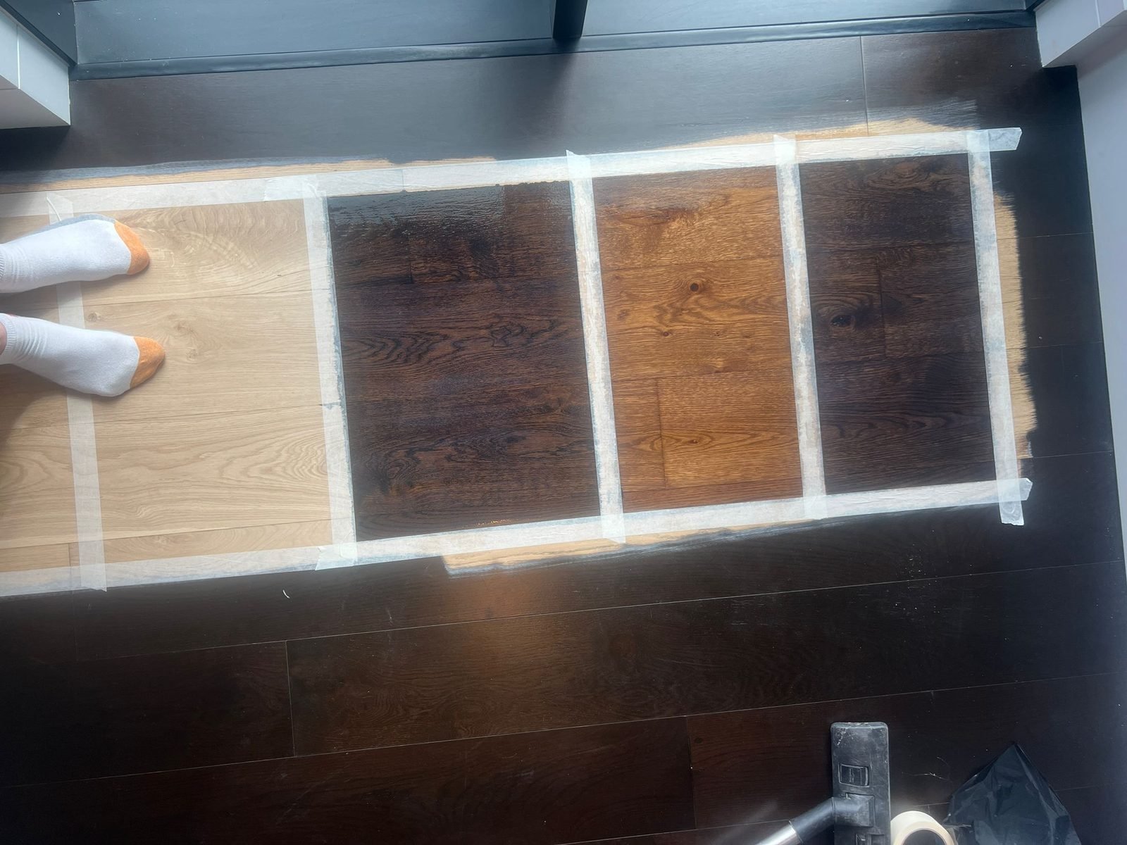 Stain samples compared on a dark floor
