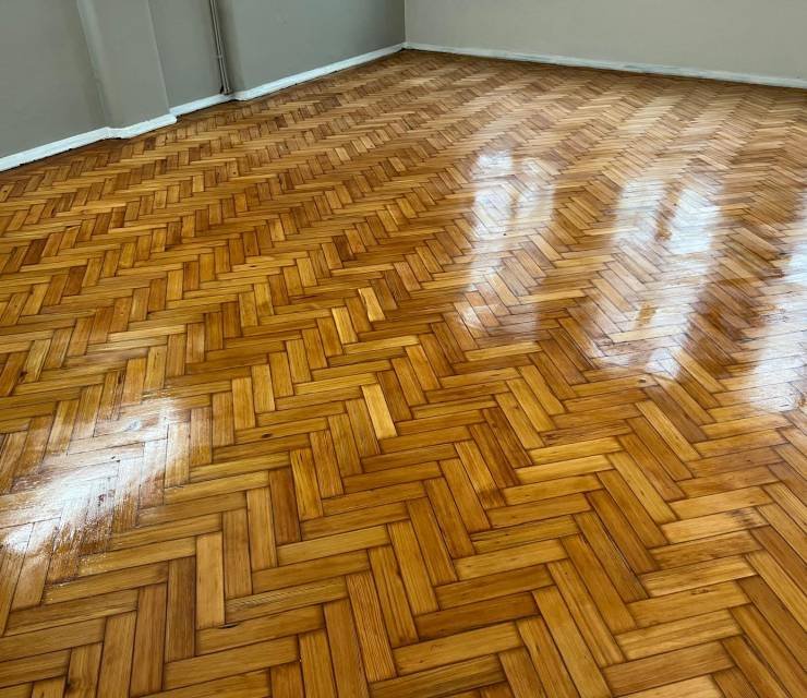 Honey-toned pine herringbone parquet floor with a high gloss finish